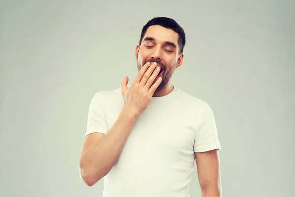 Sbadigliare l'uomo su sfondo grigio — Foto Stock