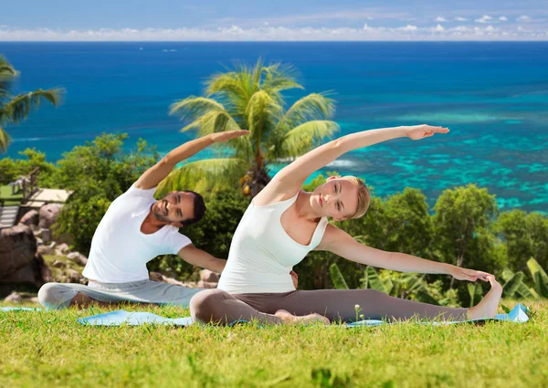 Feliz pareja haciendo ejercicios de yoga al aire libre — Foto de Stock