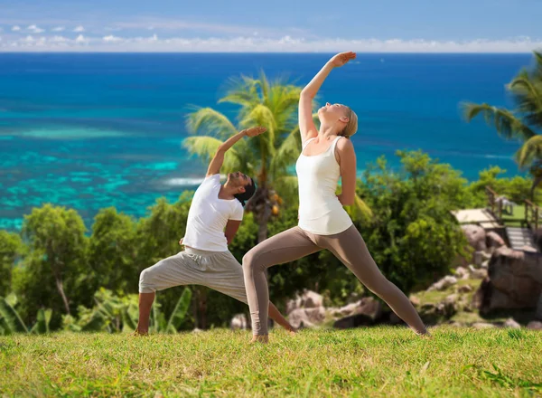 Paar yoga doen over natuurlijke achtergrond en de zee — Stockfoto