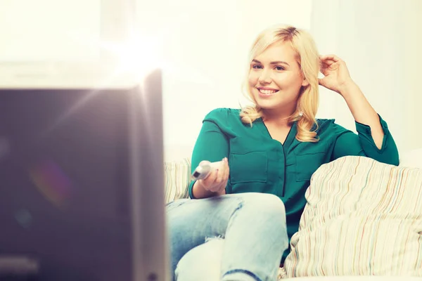 Donna sorridente con telecomando guardando la tv a casa — Foto Stock