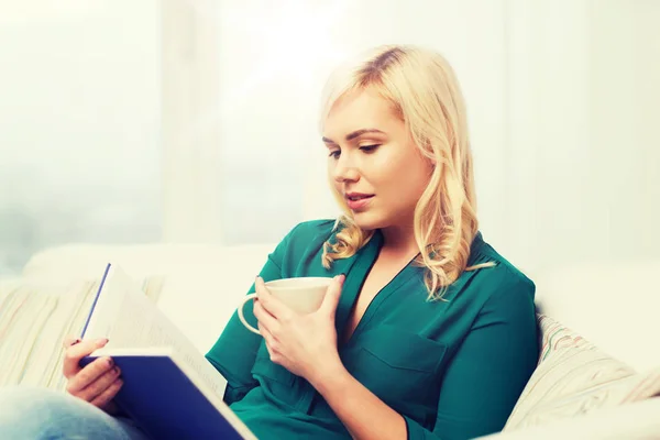 Giovane donna con libro di lettura tazza di tè a casa — Foto Stock