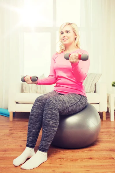 Smiling woman with dumbbells exercising at home — Stock Photo, Image
