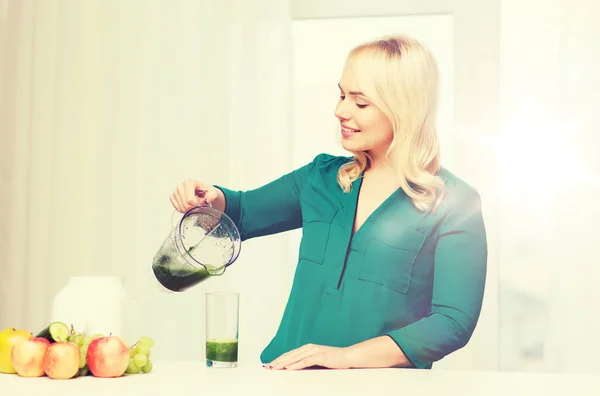 Happy woman with blender jug pouring juice at home — Stock Photo, Image