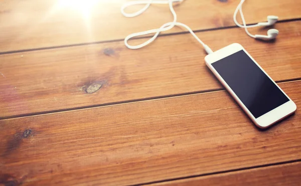Nahaufnahme von leerem Smartphone und Kopfhörern auf Holz — Stockfoto