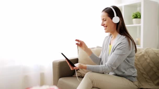 Щаслива жінка з планшетом і навушниками вдома — стокове відео