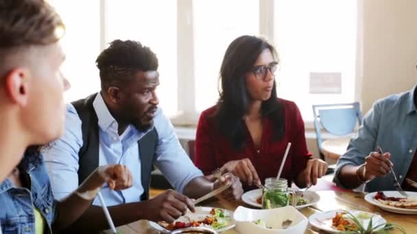 Amigos felices comiendo y hablando en el restaurante — Vídeo de stock
