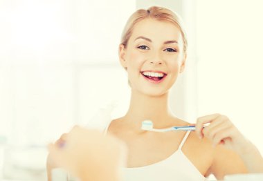 woman with toothbrush cleaning teeth at bathroom clipart