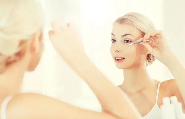Женщина чинит макияж ватным мазком в ванной комнате — стоковое фото
