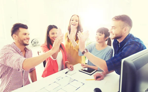 Kreativa team att göra high five på kontor — Stockfoto