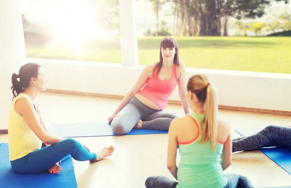 Mujeres embarazadas felices sentadas en alfombras en el gimnasio —  Fotos de Stock