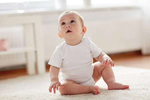 Glad liten pojke eller flicka sitter på golvet hemma — Stockfoto