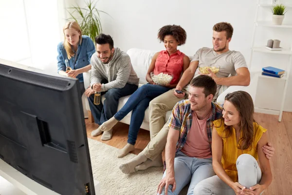Amici felici con popcorn guardando la tv a casa — Foto Stock