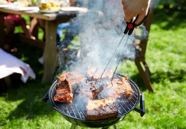 Uomo che cucina carne alla griglia alla festa estiva — Foto Stock