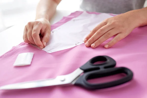 Woman with pins stitching paper pattern to fabric — Stock Photo, Image