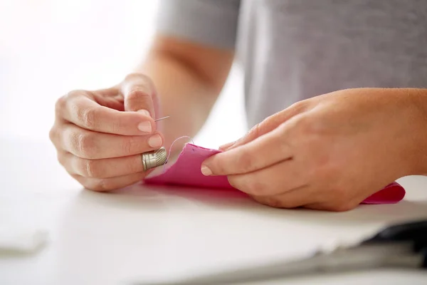 Woman with needle stitching fabric pieces — Stock Photo, Image