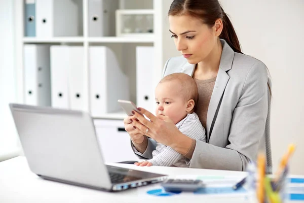 Επιχειρηματίας με το μωρό και το smartphone στο γραφείο — Φωτογραφία Αρχείου