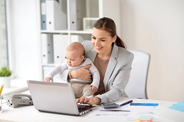 Счастливая деловая женщина с ребенком и ноутбуком в офисе — стоковое фото