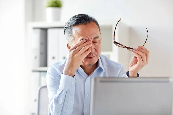 Hombre de negocios cansado con gafas en el ordenador portátil en la oficina —  Fotos de Stock