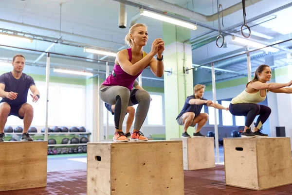Grupo de personas haciendo ejercicios de salto de caja en el gimnasio —  Fotos de Stock