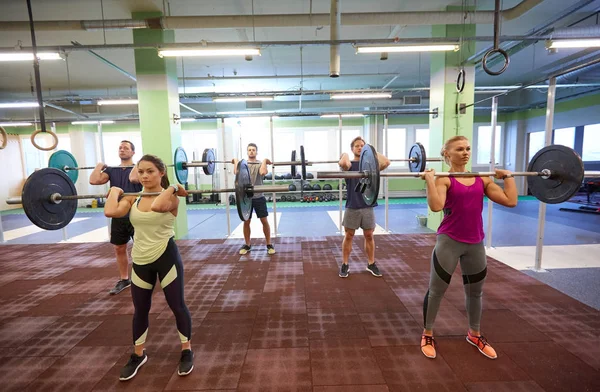 Gruppo di persone che si allenano con i bilancieri in palestra — Foto Stock