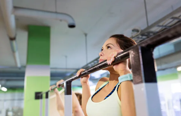 Ženy cvičení a dělá pull-up v tělocvičně — Stock fotografie