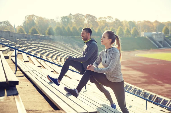 Couple stretching leg on stands of stadium — Stock Photo, Image