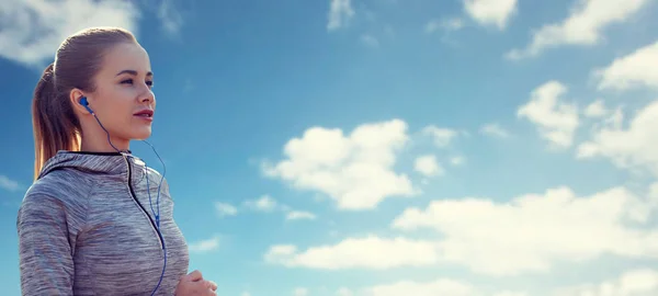 Mujer feliz con auriculares corriendo sobre el cielo azul — Foto de Stock