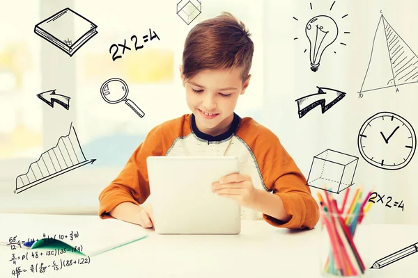 Улыбающийся мальчик с планшетным компьютером и ноутбуком дома — стоковое фото