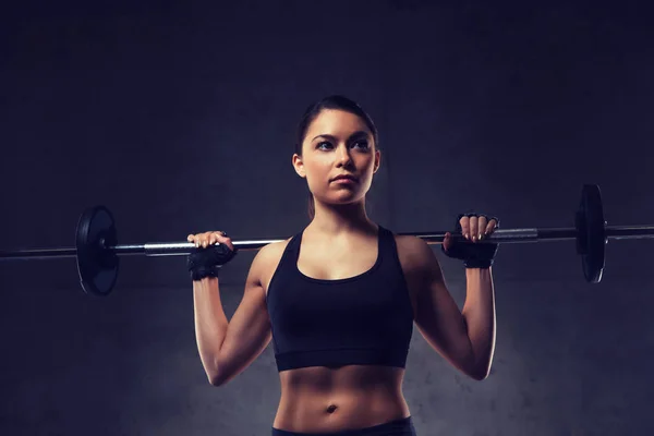 Jovem mulher flexionando músculos com barbell no ginásio — Fotografia de Stock