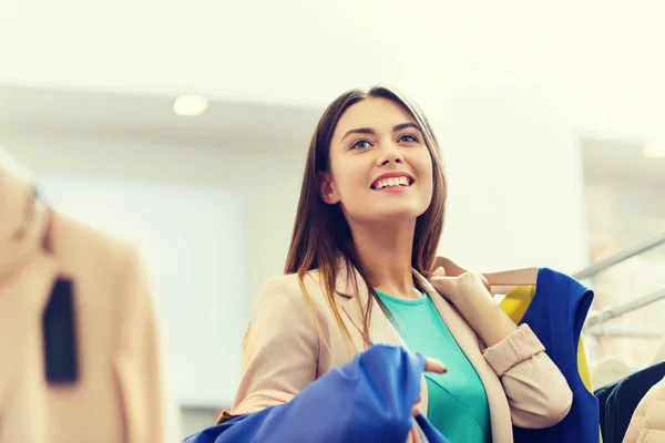 Gelukkig jonge vrouw kleding in winkelcentrum kiezen — Stockfoto