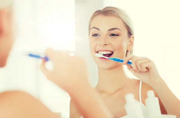 Mulher com escova de dentes limpeza dentes no banheiro — Fotografia de Stock