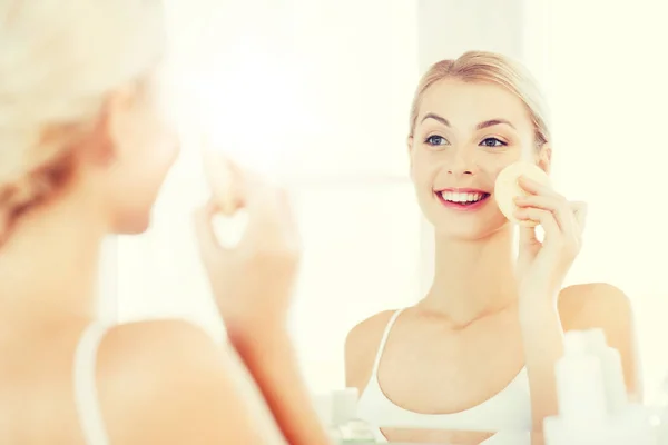 Junge Frau wäscht Gesicht mit Schwamm im Badezimmer — Stockfoto