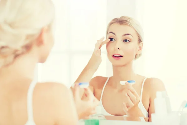 Jonge vrouw contactlenzen in te zetten op de badkamer — Stockfoto