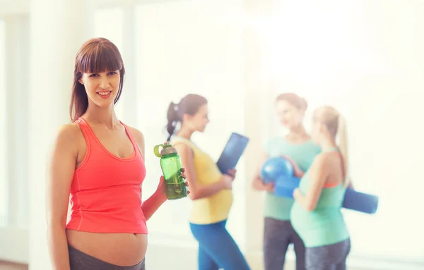 Mujer embarazada feliz con botella de agua en el gimnasio —  Fotos de Stock