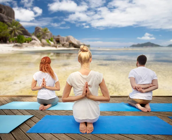Groep mensen die yoga oefeningen over strand — Stockfoto