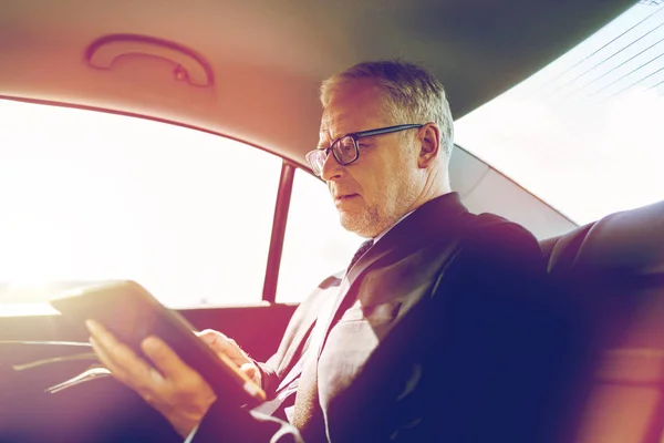 Hombre de negocios senior con la PC tableta de conducción en el coche —  Fotos de Stock