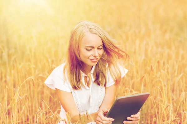 Gelukkig jong vrouw met tablet pc op graan veld — Stockfoto