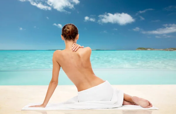 Schöne Frau im Handtuch mit nacktem Oberteil am Strand — Stockfoto