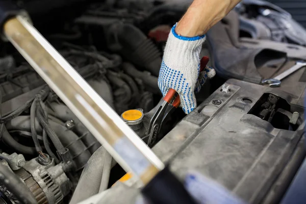 Mechanic man with pliers repairing car at workshop — Stock Photo, Image