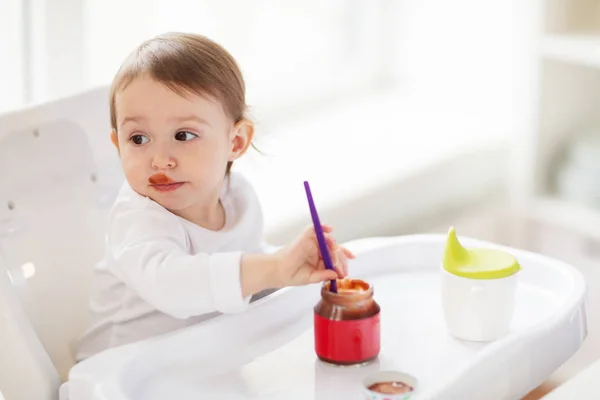 婴儿用勺子从罐子里在家里吃泥 — 图库照片