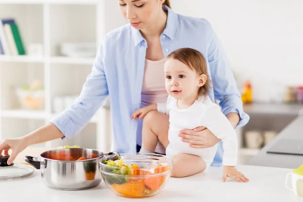 Mère heureuse et bébé cuisine légumes à la maison — Photo