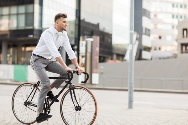 Hombre con auriculares a caballo bicicleta en la calle de la ciudad — Foto de Stock