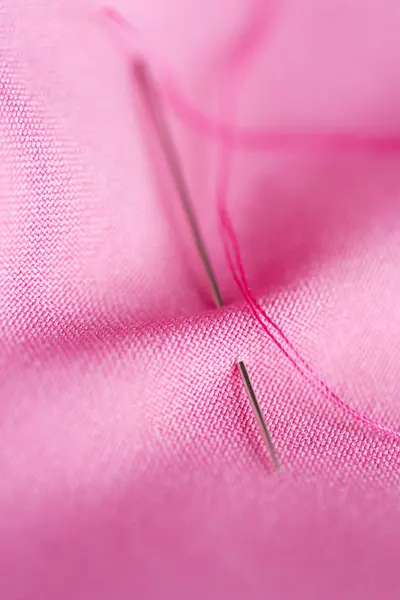 Sewing needle with thread stuck into pink fabric — Stock Photo, Image