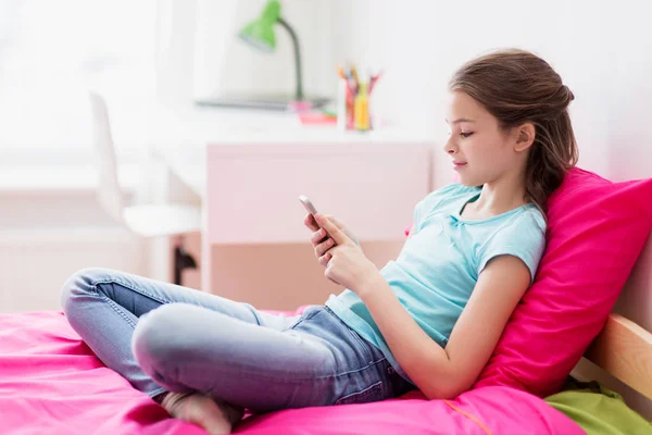 Smiling girl texting on smartphone at home — Stock Photo, Image