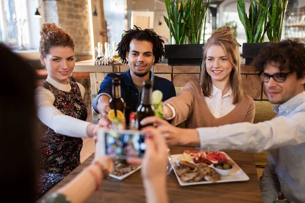 Happy vrienden rammelende drankjes in bar of café — Stockfoto