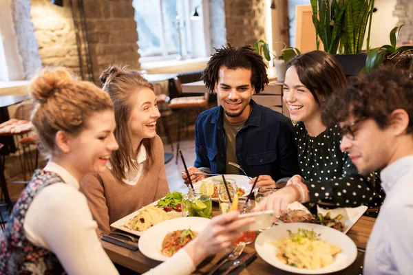 Friends with smartphone eating at restaurant — Stock Photo, Image