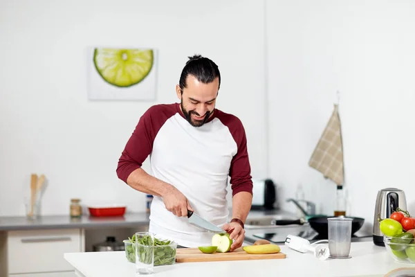 Hombre con licuadora y cocina de frutas en la cocina casera —  Fotos de Stock