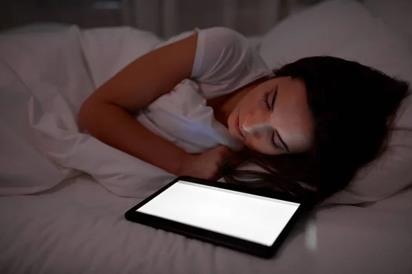 Женщина с планшетным ПК спит в постели ночью — стоковое фото