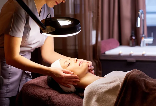 Schoonheidsspecialiste doen gezicht massage naar vrouw in spa — Stockfoto