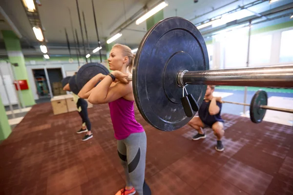 Gruppo di persone che si allenano con i bilancieri in palestra — Foto Stock